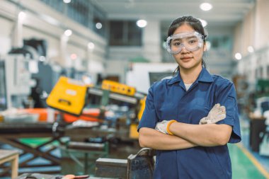 Modern metal atölyesinde portre yapan akıllı, kendine güvenen Asyalı mühendis kadın işçi.