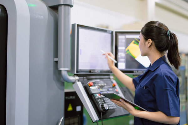 young technician engineer worker women working with CNC lathe metal machine in modern steel industry factory