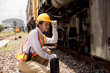 Asyalı genç mühendis tren istasyonunda çalışıyor, eski lokomotif bakım işleri motoru araba lokomotifi bakımı altında.