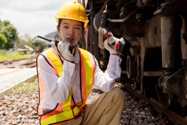 Asyalı genç mühendis tren istasyonunda çalışıyor, eski lokomotif bakım işleri motoru araba lokomotifi bakımı altında.