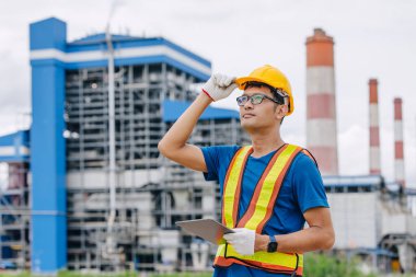 Kömür santralinde çalışan profesyonel mühendis erkek işçi, yeşil doğaya sahip elektrik santrali.