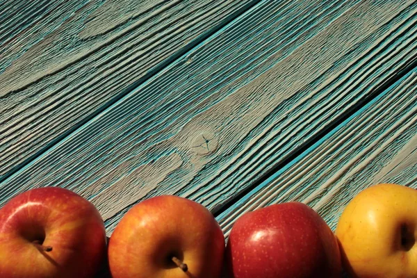 Red apples lie on blue wooden background.