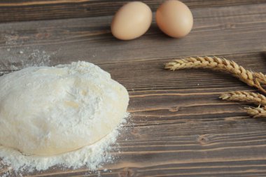 Hamur, yumurta, buğday ve un ahşap bir masada yatıyor.