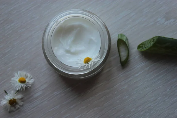 Glas Mit Weißer Kosmetikcreme Aloe Und Kamille Auf Beigem Hintergrund lizenzfreie Stockbilder