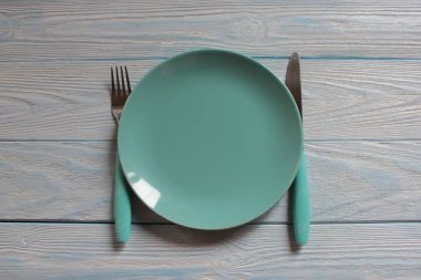 Ahşap arka plan üzerinde mavi boş çanak, bıçak ve çatal.