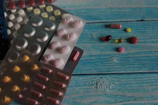 Pills, capsules and vitamins lie on a wooden table.