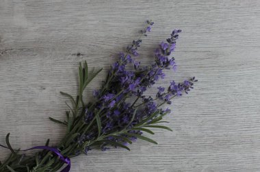 Mor kurdeleli bir demet lavanta gri ahşap bir yüzeyde yatıyor..