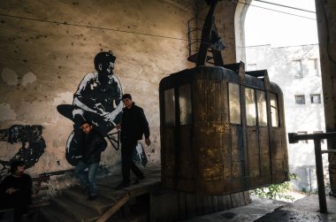 Chiatura, Georgia - October 20, 2016: Local people leave old retro aerial old tram ropeway or cable car leading to the abandoned area in Chiatura. Industrial landmark of Georgia. clipart