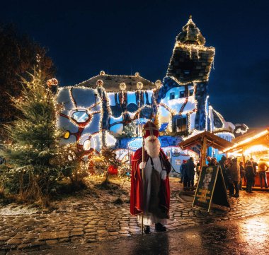 Abensberg, Almanya - 8 Aralık 2017: Saint Nicholaus Noel aydınlatmaları ve dekorasyon mal parlayan yükleri ile Hundertwasser Sanat Müzesi Kunsthaus önünde duruyor.