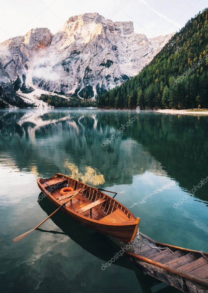 Boats and slip construction in Braies lake with crystal water in background of Seekofel mountain in Dolomites in morning, Italy Pragser Wildsee