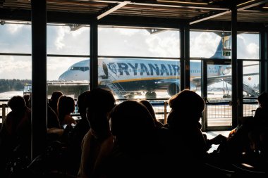 Memmingen, Bavyera, Almanya - 9 Aralık 2017: İnsan siluetleri havaalanında uçak Ryanair karşı terminal bekliyor