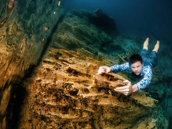 Climber man holds cliff underwater