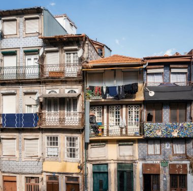 Pencereleri ve süslü metal balkon parmaklıkları olan geleneksel Portekiz evi. Seramik seramik kiremitleri olan eski bina duvarı.