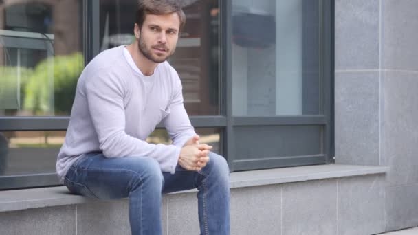 Anxieux sérieux bel homme assis à l'extérieur du bureau — Video