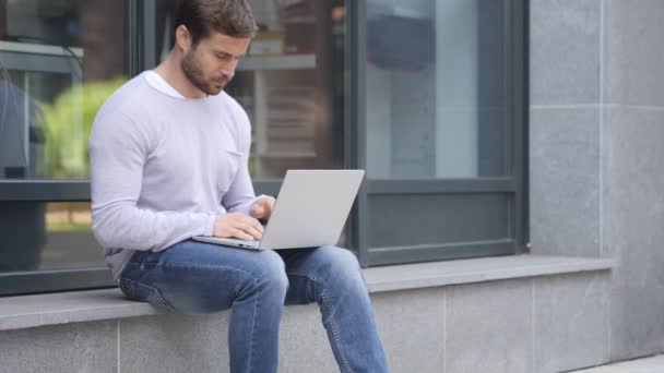 Tense bel homme avec maux de tête de travail sur ordinateur portable assis à l'extérieur du bureau — Video