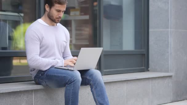 Homem animado comemorando o sucesso no laptop sentado em escadas — Vídeo de Stock