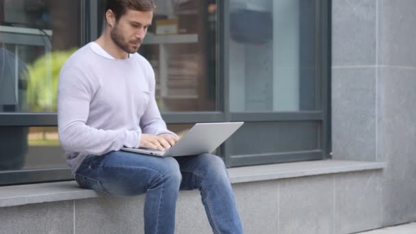 Przystojny mężczyzna pracy na laptopie, podczas gdy siedzi na zewnątrz pakietu Office — Wideo stockowe