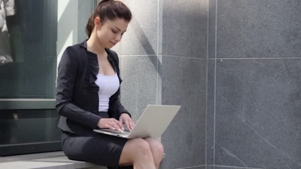 Бізнес жінка залишивши після сидять за межами офісу і працюють на ноутбук — стокове відео