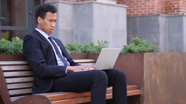 Designer espantado se perguntando ao usar o laptop sentado no banco — Vídeo de Stock