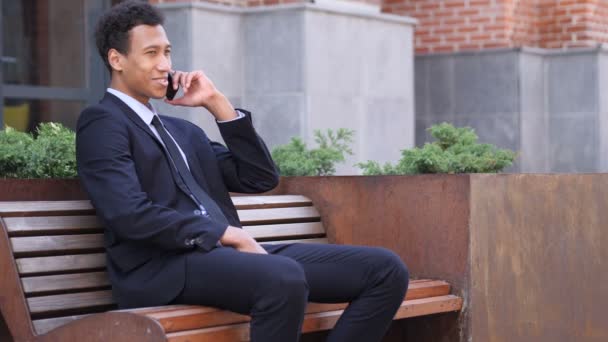 Telefongespräch, afrikanischer Geschäftsmann bei Anruf dabei, während er auf Bank sitzt