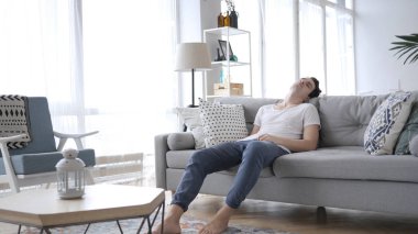 Evde kanepede uyuyan yorgun genç adam