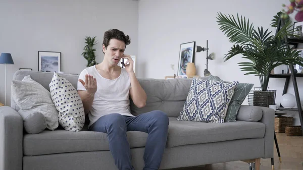 Angry Screaming Man Talking on Phone, Sitting on Sofa