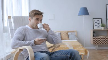 Yetişkin adam kahve içme rahat sandalyede otururken rahatlatıcı