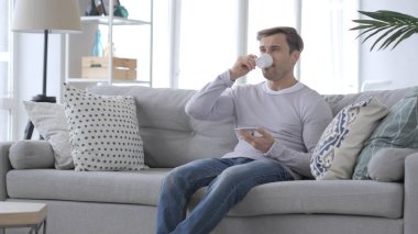 Yetişkin adam kahve içme ve kanepede rahatlatıcı