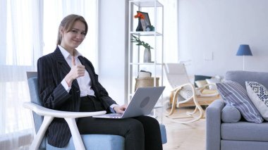 Başparmak yukarıya kameraya bakarak, iş yerinde genç kadın tarafından