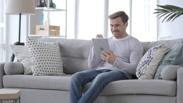 Excited Man Celebrating Success, while Using Tablet Computer