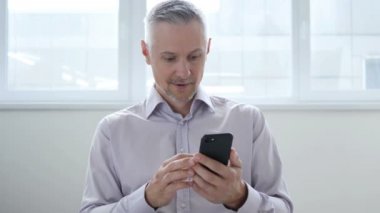 Orta yaşlı adam heyecanlı Smartphone kullanarak süre başarı için