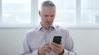Orta yaşlı adam üzgün Smartphone kullanarak süre kaybı için