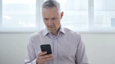 Smartphone kullanarak işadamı şok, şaşırmış gibi orta yaşlı