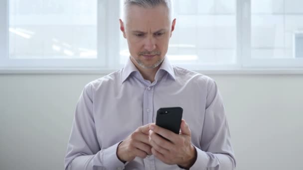 Hombre de mediana edad navegando en el teléfono inteligente, utilizando Internet — Vídeos de Stock