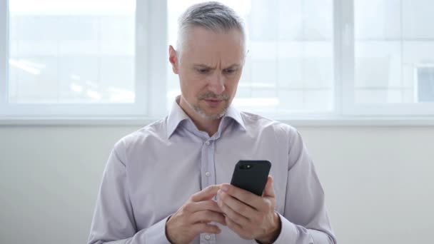 Uomo di mezza età sconvolto per la perdita durante l'utilizzo di smartphone — Video Stock