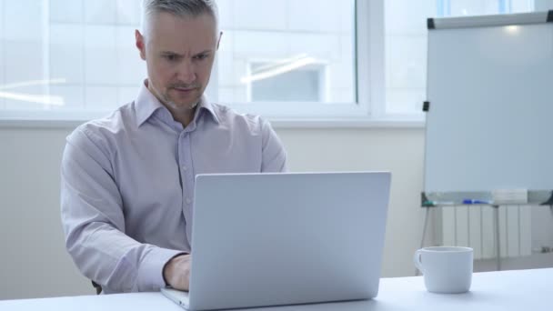 Предприниматель среднего возраста покидает офис после закрытия ноутбука на работе — стоковое видео