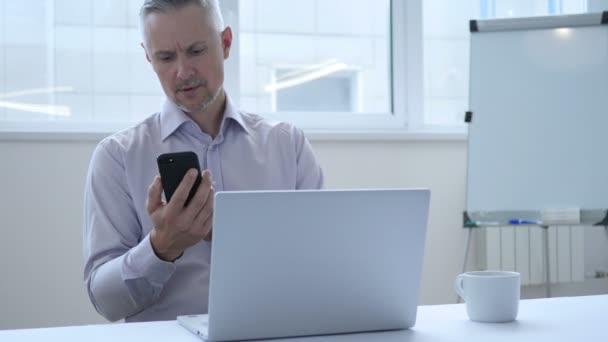 Geschäftsmann mittleren Alters beschäftigt mit Smartphone für die Arbeit im Büro — Stockvideo