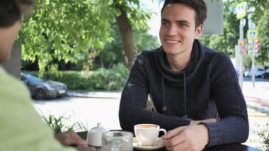 Genç adam Cafe Teras otururken arkadaşıyla konuşuyor