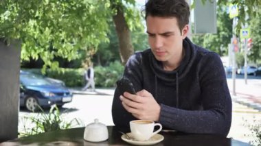 Adam Cafe Teras otururken Smartphone kullanarak