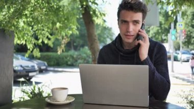 Cafe Teras içinde Laptop üzerinde çalışırken adam Talking telefon