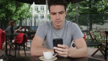 Adam Cafe Teras otururken Smartphone kullanarak