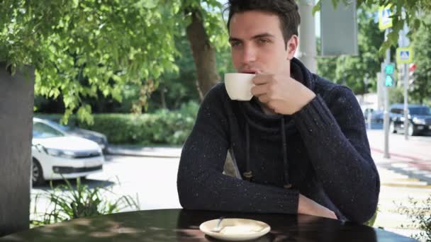 Young Man drinken koffie zittend in Cafe terras — Stockvideo