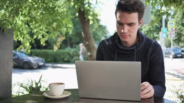 Eccitato uomo che celebra il successo sul computer portatile seduto in terrazza Cafe — Video Stock