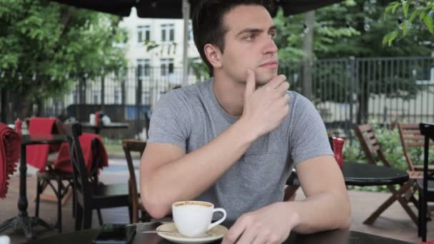 Denken peinzende jonge Man zitten in een Cafe terras — Stockvideo
