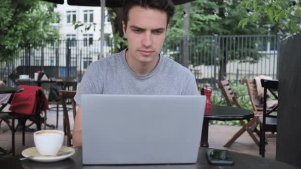 Мужчина разговаривает по телефону и использует ноутбук в кафе Терраса — стоковое видео