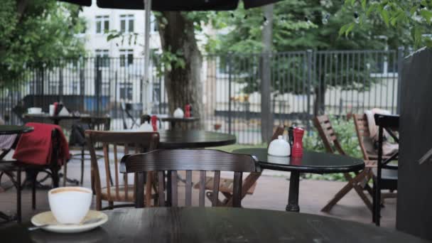 Mann kommt und sitzt auf Caféterrasse, um am Laptop zu arbeiten — Stockvideo