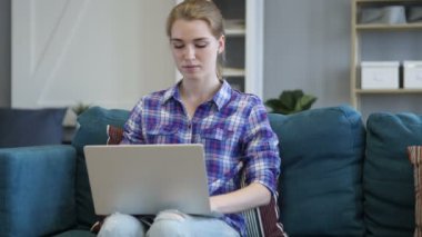 Kanepenin içinde Laptop üzerinde çalışan genç kadın yorgun