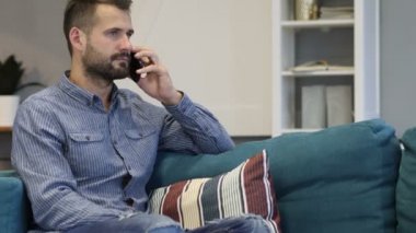 Yatak odasında kanepede oturan telefonda konuşan adam