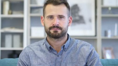 Başparmak aşağı kameraya bakarak işyerinde yetişkin adam tarafından