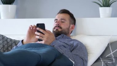 Adam akıllı telefon kullanarak Lying yatakta iken